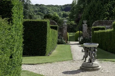 formal garden hedge plants neatly clipped around a statue and gates